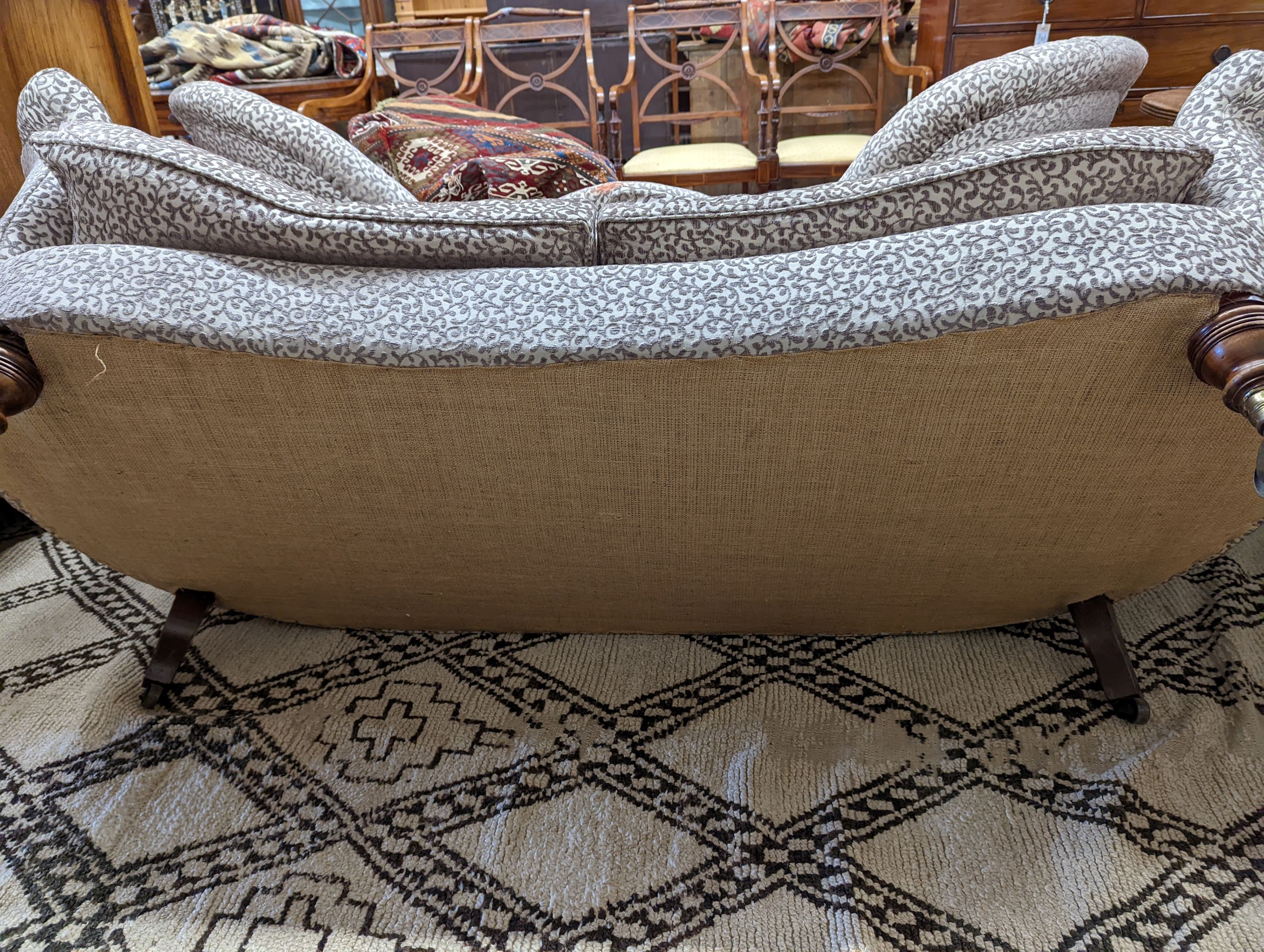A Victorian upholstered settee with turned walnut legs, fitted brass castors, length 188cm